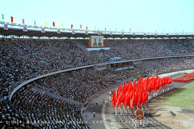 1965年，第二届全运会在北京举行。图为9月11日，在开幕式上，仪仗队抬着国徽、举着红旗引导运动员入场。