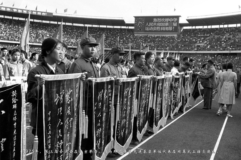 1975年，第三届全运会在北京举行。图为群众体育先进基层单位代表在闭幕式上接受奖旗。