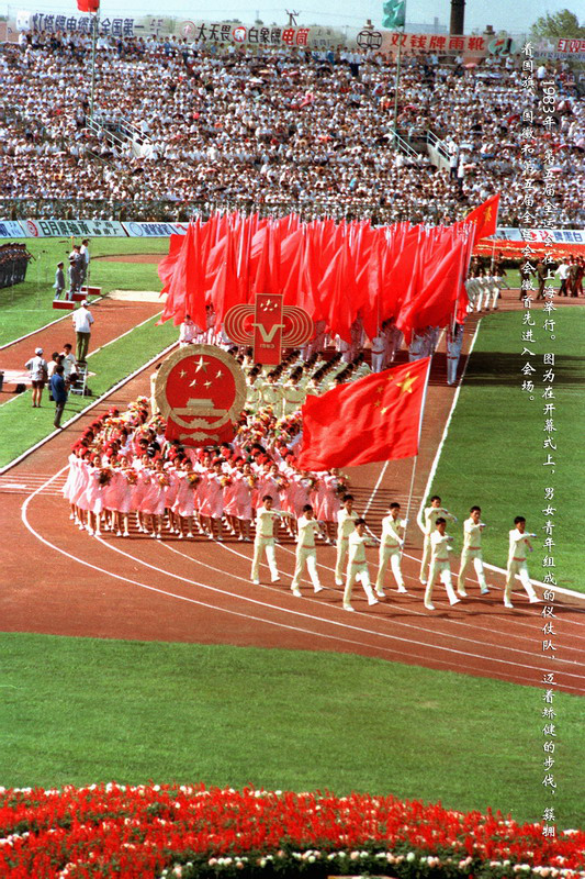 1983年，第五届全运会在上海举行。图为在开幕式上，男女青年组成的仪仗队，迈着矫健的步伐，簇拥着国旗、国徽和第五届全运会会徽首先进入会场。