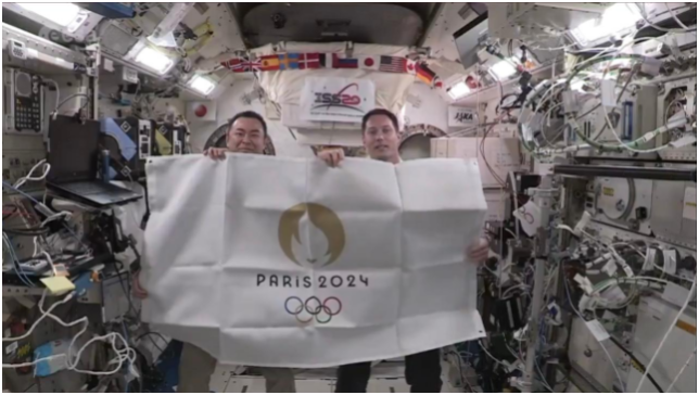 日本和法国宇航员也在太空中共同打开奥林匹克会旗和印有2024年巴黎奥运会会徽的旗帜