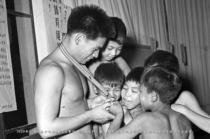 1959年，第一届全运会在北京举行。图为孩子们在争看第一届全运会游泳冠军穆祥雄获得的全运会奖章。