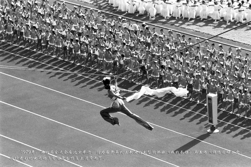 1979年，第四届全运会在北京举行。图为在开幕式上表演的大型团体操《新的长征》第五场《锦绣前程》中，披纱着彩的女运动员自背景台顶篷上滑降而下。