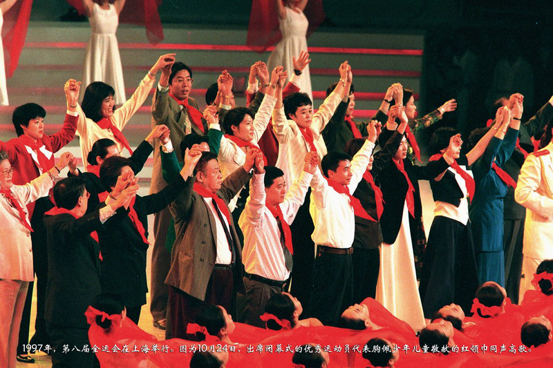1997年，第八届全运会在上海举行。图为10月24日，出席闭幕式的优秀运动员代表胸佩少年儿童敬献的红领巾同声高歌。