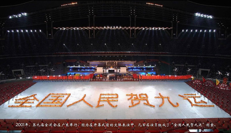 2001年，第九届全运会在广东举行。图为在开幕式前的文体表演中，几百名演员组成了“全国人民贺九运”图案。